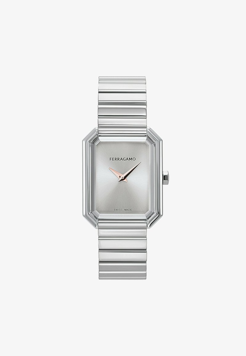 Hõbedane kaheksanurkne kell harjatud metallist kellapinnaga. Kellel on minimalistlik disain, õhuke hõbedane link-käevõru ja roosakuldne tunni näitaja. Šveitsi valmistatud.