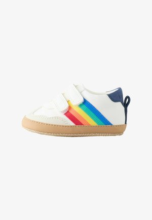 Baskets blanches à deux bandes Velcro, avec un motif à rayures arc-en-ciel, une semelle en caoutchouc couleur tan, et un accent bleu au talon.