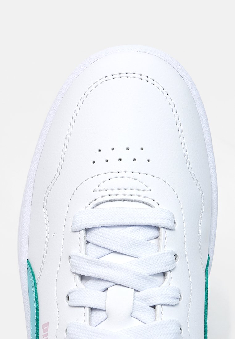 Zapatilla deportiva de cuero blanco con superficie texturizada, cordones blancos, detalles verdes en los lados y perforaciones cerca de la punta para ventilación.