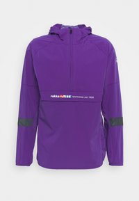 Giacca a vento viola con zip parziale frontale, cappuccio regolabile, dettagli neri sulle maniche e un pannello con logo che riporta "rukka sportswear est. 1950."