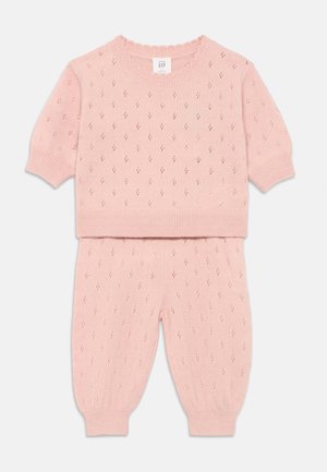 Ensemble en tricot rose composé d'un haut à manches courtes et d'un pantalon fuselé. Le design comprend des motifs en diamant ainsi que des poignets, un ourlet et un col côtelés.