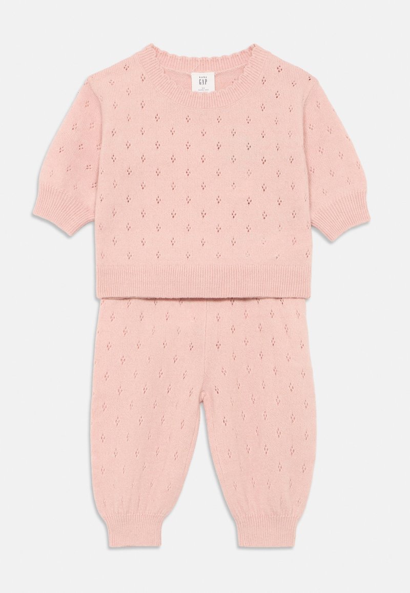 Conjunto de dos piezas de punto rosa que incluye un top de manga corta y pantalones ajustados. El diseño presenta patrones de diamante y puños, dobladillo y escote acanalados.