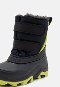 Schwarzer wasserdichter Winterstiefel mit grauem Fellfutter, Klettverschlüssen und grüner Gummisohle. Verfügt über ein strukturiertes Obermaterial zur Isolierung.