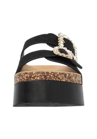 Sandales à plateforme noires avec deux brides en daim. Comprend une boucle en forme de cœur scintillante dorée, une semelle intermédiaire en liège et une semelle noire texturée.