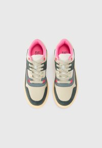Des sneakers avec une tige beige et vert foncé, des accents gris, une doublure rose, et des détails perforés. Semelle en caoutchouc de couleur claire.