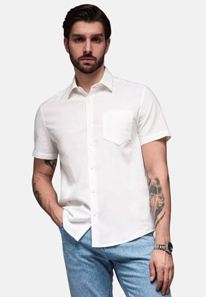 Chemise blanche à manches courtes avec une poche poitrine. Fabriquée en tissu léger, elle présente un design épuré et un col standard.