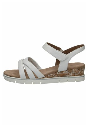 White strappy sandal with a soft, textured footbed; features a cork heel with floral patterns; rubber sole for grip.