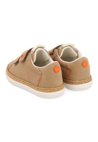 Zapatillas de lona color marrón claro con suelas blancas y un acento de yute trenzado. Con detalles en naranja y una correa de gancho y bucle para facilitar el uso.