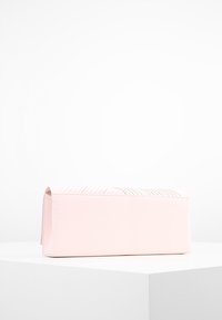 Růžová obdélníková kabelka vyrobená z umělého materiálu s hladkým povrchem. Obsahuje vertikální šití na vrchu a plochý základ pro stabilitu.