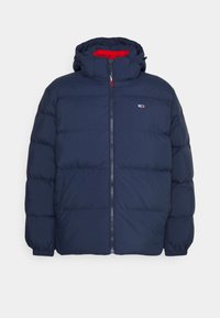Chaqueta de plumón azul marino con capucha, cremallera frontal, puños elásticos y pequeño logo rojo, blanco y azul en el lado izquierdo del pecho.