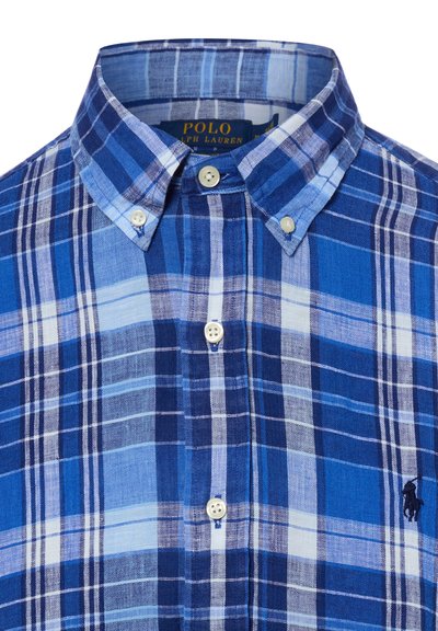 Chemise à carreaux bleus et blancs avec col boutonné et petit logo brodé sur la poitrine.