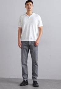 Polo alb cu mânecă scurtă, cu guler, asociat cu blugi gri și pantofi din piele negri. Design simplu, casual, cu o croială lejeră.