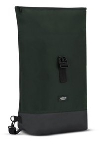 Tmavě zelený batoh s hladkým povrchem, se zipem na vrchu, předním popruhem na přezku a černým dnem. Malá značková nálepka na přední straně.