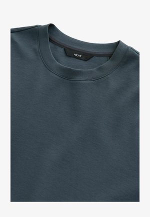 Sweatshirt sombre bleu canard à col rond, fabriqué en tissu doux, arborant un design simple avec une texture lisse et sans motifs ni accents visibles.