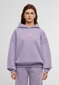 Violetinė maikutė su gobtuvu, pagaminta iš minkštos medžiagos, su laisvu siluetu, turinti dideles rankoves. Rožinės spalvos „felicious“ logotipas yra centre ant krūtinės.