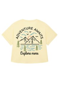 Geel T-shirt met korte mouwen met een grafiek van een berg en een meer. De tekst luidt "AVONTUUR WACHT" en "Verken meer" in het zwart.