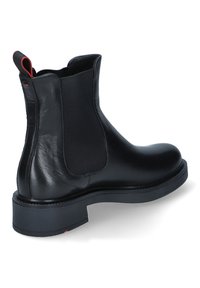 Stivale Chelsea in pelle nera con pannelli elastici laterali e punta leggermente arrotondata. Presenta un'etichetta rossa a contrasto e una suola robusta e testurizzata.