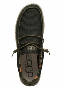 Scarpa nera in rete slip-on con accenti verdi e soletta con motivo mimetico. Presenta una punta arrotondata e una suola grigia a contrasto.