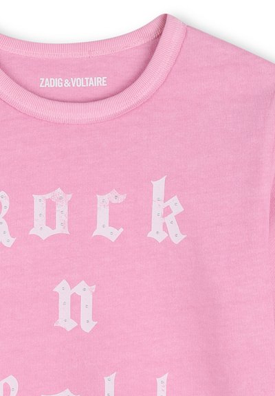 Różowa bluza z okrągłym dekoltem ozdobiona białymi literami w stylu staroangielskim, częściowo układającymi się w słowo, zdobiona małymi kryształkami, oznakowana marką Zadig & Voltaire.