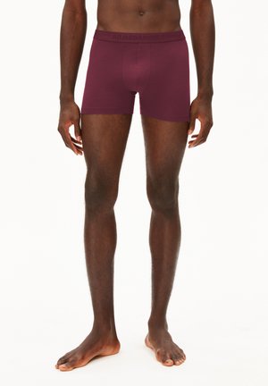 Boxer corti bordeaux con design aderente, realizzati in tessuto morbido, dotati di un elastico in vita con il nome del marchio impresso.