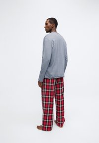 Grå långärmad skjorta av lätt tyg kombinerad med röda och svarta rutiga pyjamasbyxor, med en lös passform och raka ben.