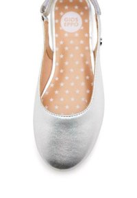 Zapato plano plateado con punta redondeada, parte superior metálica brillante y plantilla de un melocotón claro con patrones de estrellas blancas.