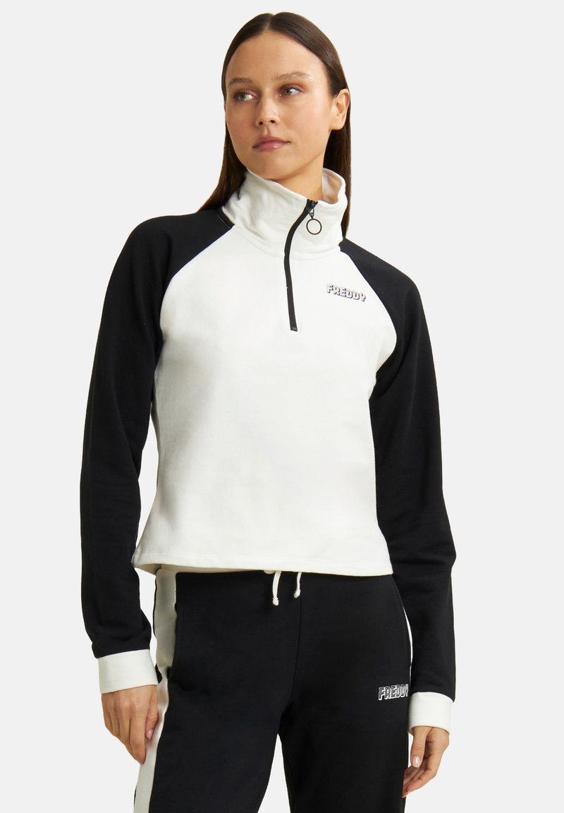 Sudadera con cremallera de un cuarto en blanco y negro con mangas ranglán, que presenta una textura suave y logo en el pecho. Dobladillo con cordón ajustable.