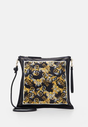 Kwadratowa torebka z czarnym satynowym wykończeniem i misternymi złoto-białymi wzorami w kształcie zawijasów. Posiada odpinany czarny pasek i złote okucia.