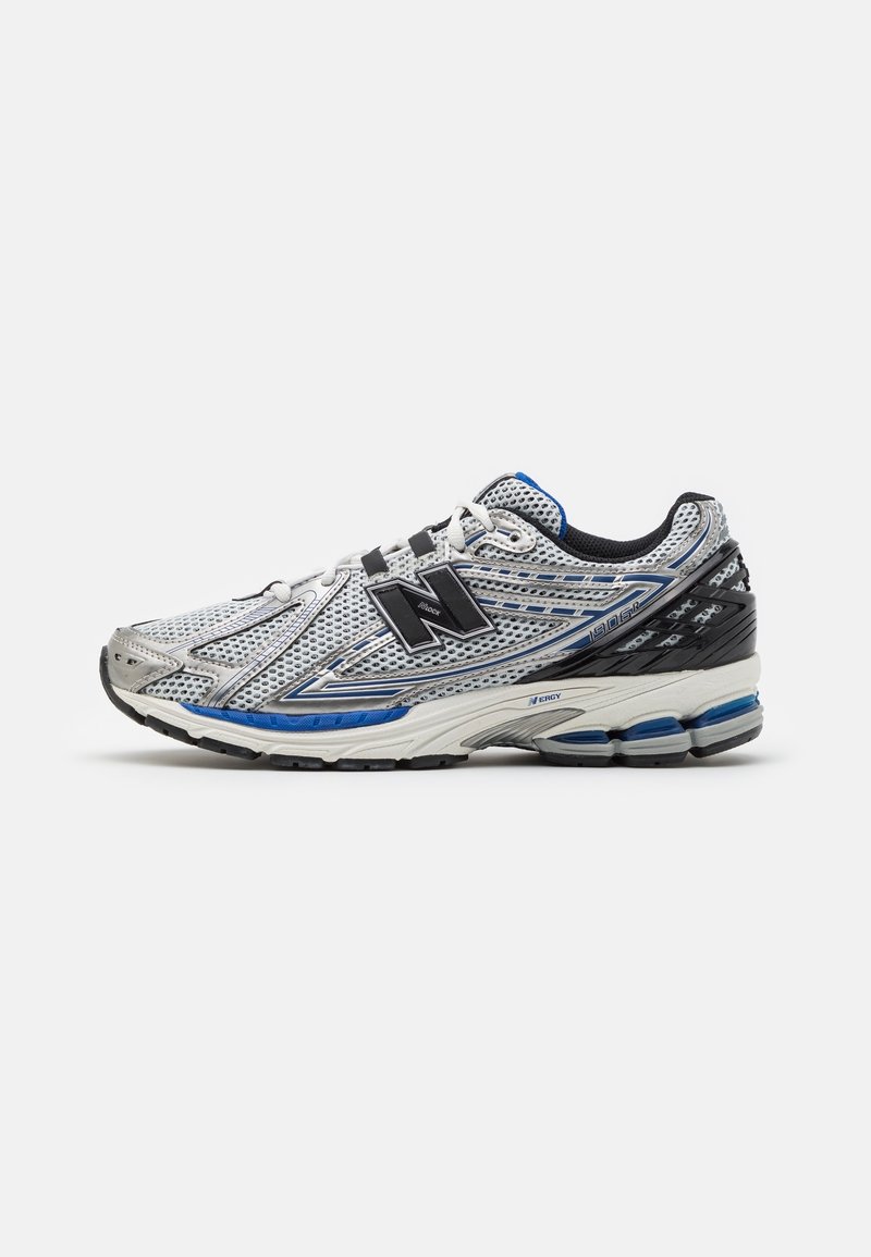 Grå och blå New Balance löparsko med meshuppskatt, svart hälstöd, vadderad vit sula och svart "N"-logotyp på sidan.
