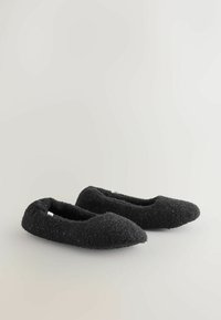 Black felted slippers with a slim, rounded design. Textured surface and a soft, cozy appearance. No visible hardware or accents.