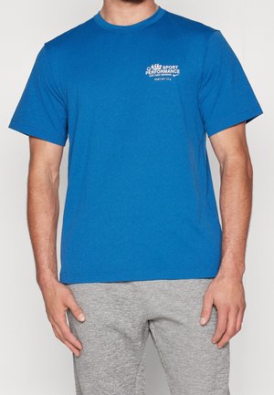 Camiseta azul de manga corta hecha de una mezcla de algodón. Presenta un escote redondo y un pequeño estampado gráfico en el lado izquierdo del pecho.