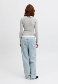 Gray long-sleeve shirt paired with light blue wide-leg jeans, featuring two back pockets and a relaxed fit, set against a plain background.