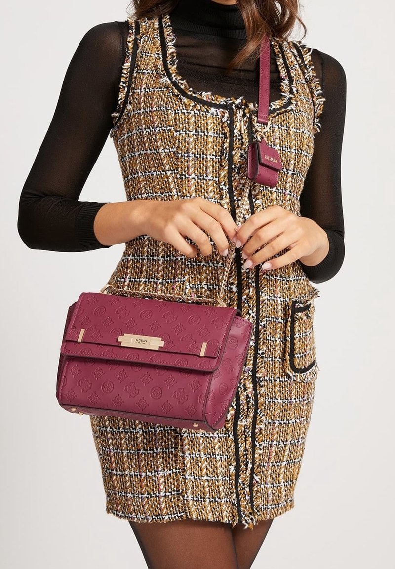 Bordeaux læderhåndtaske med præget logo-mønster, guldfarvet hardware og aftagelig rem. Stylet med en tekstureret, multicoloret tweedkjole.