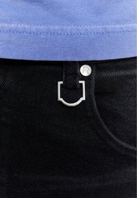 Blugi din denim inchis au un nasture argintiu cu logo si un detaliu distinctiv in forma de patrat pe talie, completati de o camasa bleu deschis deasupra.