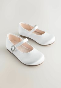 Scarpe Mary Jane in satin bianco con punta tondeggiante, suola piatta e una fibbia decorativa in argento sulla cinghia. Rivestimento interno di un morbido rosa visibile all'interno.