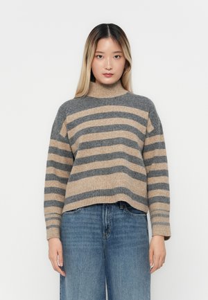 Stripet høyhalset genser i grå og beige ullblanding. Bokseformet design med ribbestrikkede mansjetter og kant. Kombinert med lyseblå vide jeans.