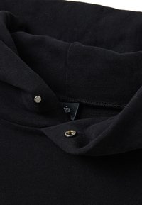 Sudadera negra con una textura suave, que cuenta con un cuello doblado, un cierre de broche metálico y una etiqueta de tela en la zona del cuello.