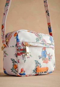 Sac bandoulière à motif floral, fabriqué en tissu durable, avec des accents dorés, une poche zippée et une sangle réglable.