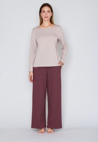 Lange mouwen lichtroze top met een bootnek, gecombineerd met wijde bordeaux gestreepte broek. Zacht materiaal en casual ontwerp.