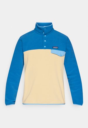 Fleecepulloveri, jossa on sininen kaulus ja hihat, kermaisen värinen runko ja pieni rintatasku. Varustettu neljällä napilla ja logoplaasilla.