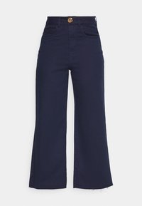 Marinblå vida byxor tillverkade av en bomullsmix. Har en framknappstängning, två framfickor och fransade fållen.