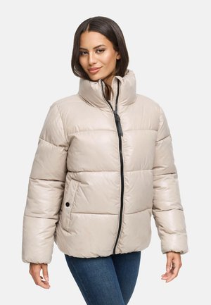 Giacca puffer beige con colletto alto, texture trapuntata, zip nera e due tasche laterali, indossata sopra jeans scuri.