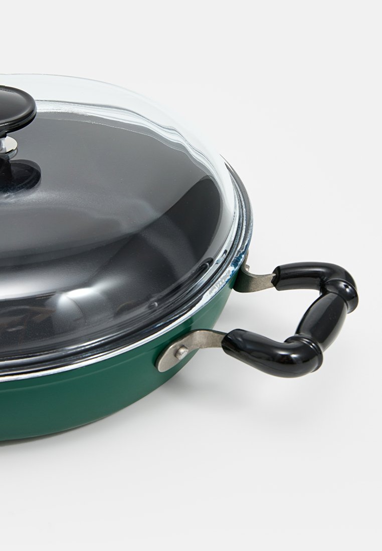 Padella verde con coperchio in vetro, pomello nero e dettagli argentati. Presenta un manico nero con un design curvo per la presa.