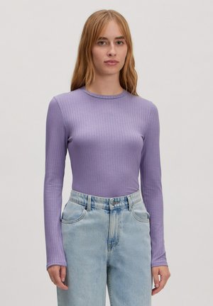 Langmouwtop in licht lila ribstof, met een ronde halslijn en een getailleerde snit, gecombineerd met hooggeremde lichtblauwe jeans.
