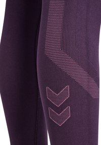 Paarse legging met een gestructureerd patroon en roze zigzag accenten aan de zijkant, gemaakt van zacht materiaal en met een aansluitend ontwerp.