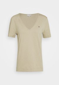 Camiseta de pico en color caqui claro con mangas cortas, hecha de una tela suave. Cuenta con un pequeño logotipo bordado en el lado izquierdo del pecho.
