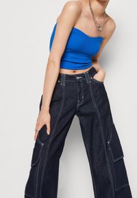 Blå randig strapless topp kombinerad med mörk denim bredbenta cargobyxor med vit söm och flera fickor. Inkluderad silver kedjehalsband.