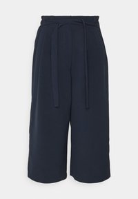 Navy wide-leg trousers made of a smooth fabric, featuring a tie waist and pleated design, with hem finishing just above the ankle.
