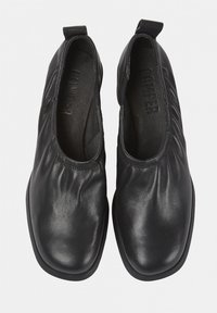 Chaussures à enfiler en cuir noir avec des détails froncés, bout arrondi et semelle en caoutchouc plate. L'intérieur présente un revêtement texturé.