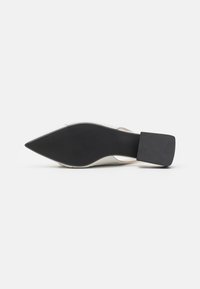 Escarpin à bout pointu avec une tige synthétique blanche, une semelle en caoutchouc noire et un talon carré. Présente une légère texture sur la surface du talon.